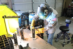 Shawn welding metal in a workshop with protective gear on